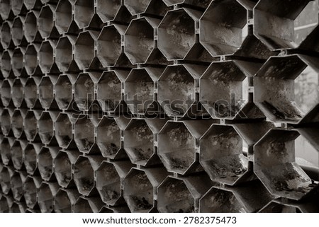Abstract geometric hexagonal pattern on a textured metal architectural grille. Ideal for industrial design, background, and construction.