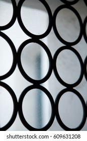 Abstract geometric pattern arrangement of stacked circular wrought iron rings in Spanish style leaded window frame