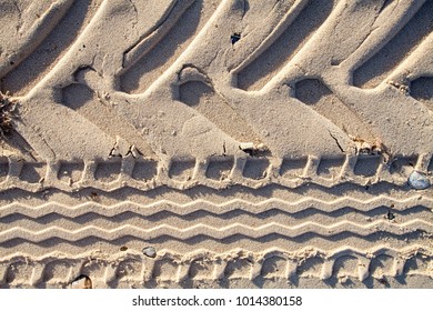 Abstract Geometric Pattern Background Image. Tractor Tyre Tracks In Sand. Close Up Of Zigzag Tire Tread Imprint On The Beach.