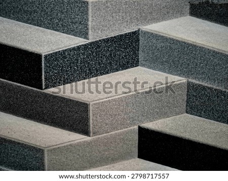 Abstract geometric pattern created by textured stone tiles in varying shades of grey, arranged to create a three-dimensional staircase illusion. Modern architectural surface design with contrasting light and dark granite-like textures, suitable for luxury interior concepts and background textures.