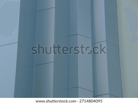 Abstract geometric pattern of light blue aluminum composite panels (ACP) forming the vertical fluting structure of a modern commercial skyscraper wall.