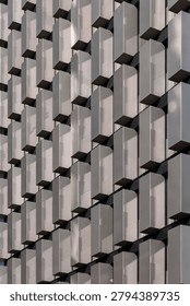 Abstract geometric pattern of a modern building facade with metallic panels. Abstract architectural background featuring a close-up of a modern skyscraper facade with repeating 3D rectangular geometric elements and futuristic metal panels. Perfect for design, corporate identity, and construction concepts.