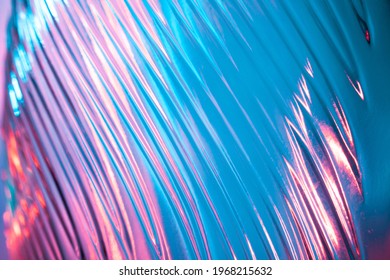 Abstract Glass Background. Texture Of Wavy Glass Illuminated With Multi-colored Light. Pink And Blue Stains. Close Up. Flares On Glass