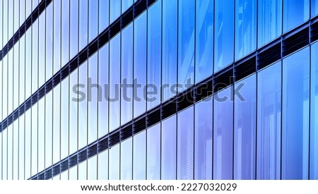 Abstract glass facade with strict geometric lines and rectangles in blue base color with brightness gradients, facade of glass high-rise building