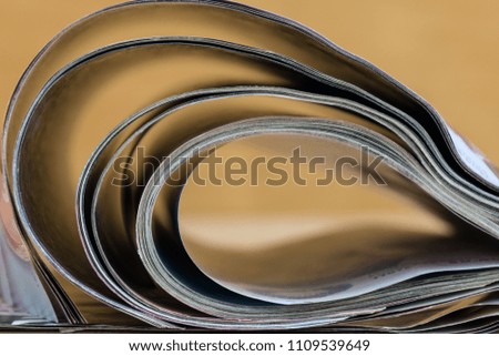 Abstract glossy magazines on wooden background. Open magazine with curved pages. Copy space. 