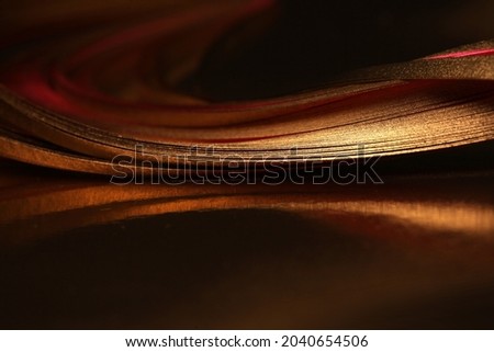 Abstract Gold (bronze) wave lines paper ribbons on black empty background.