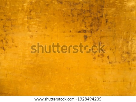 Abstract golden background for art decor with matte texture and variation shades of Fortuna Gold color. Metallic paint on vintage wall, gilded and aged effect with brown stains on surface.