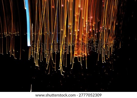 Abstract golden light rain and glowing vertical streaks on dark background with long exposure photography.