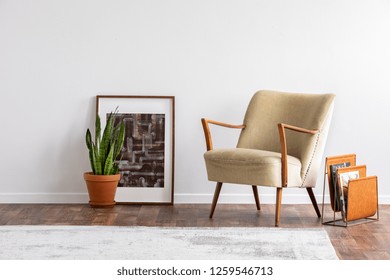 Abstract Graphic In Wooden Frame Next To Green Plant In Ceramic Pot And Elegant Beige Armchair And Orange Magazine Rack, Real Photo