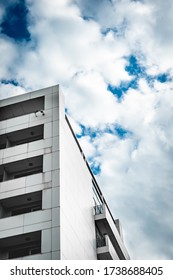 Abstract Gray Building Top Corner With Glass Balconies And Reflection Of Sky In The Windows.