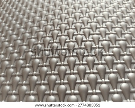 Abstract grey geometric pattern with repetitive teardrop shapes and a soft bokeh background.
