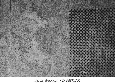 Abstract grey stone surface background with rectangular section of perforated metal dots, creating a modern industrial texture
