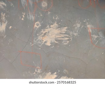 Abstract grey wall with texture featuring paint splotches and orange streaks.