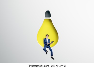 Abstract Image Of Attractive Young European Businessman Sitting On Abstract Hanging Light Bulb Chair And Using Laptop On White Background. Idea, Innovation, Work Culture And Inspiration Concept