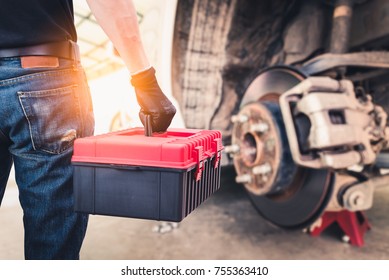 The abstract image of the back of technician hold a toolbox and blurred disc brake is backdrop. the concept of automotive, repairing, mechanical, vehicle and technology. - Powered by Shutterstock