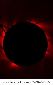 An abstract image of a black baking pan under which a red light shines.