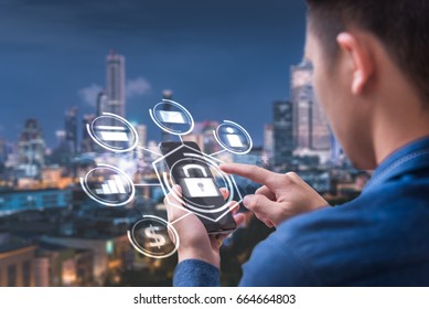 The Abstract Image Of Business Man Point To The Hologram On His Smartphone And Blurred Cityscape Is Backdrop. The Concept Of Communication Network Cyber Security Internet Of Things And Internet.