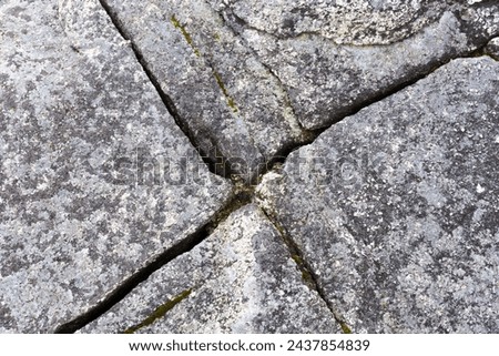 An abstract image of a crisscross pattern on grey broken stones. 