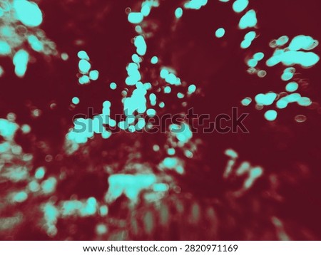 An abstract image featuring a background of diffused light and a blend of colors—predominantly deep, rich maroon and dark reddish-brown—created by the reflection of morning sunlight off a dense area of ​​shrubs.