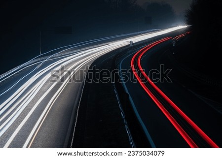 Abstract image of night traffic lights on the road. Car light trails at night in curve asphalt road. Long exposure showing movement of cars from bridge or drone