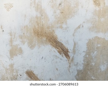 An abstract image of a pale wall with multiple irregular splotches of brown discoloration and rough brush marks.
