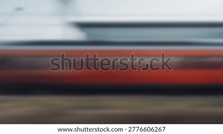 Abstract image of a speeding train, captured with a motion blur effect, conveying speed and travel. The trains red and white colors are visible.
