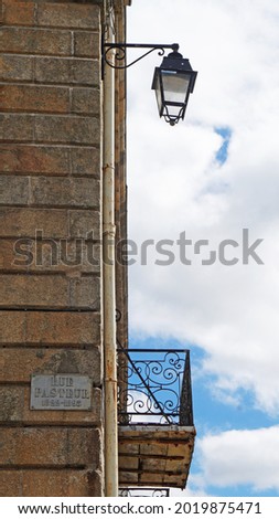 abstract image with a street light on a stone wall and a balcony against the blue sky, Lorient, Brittany, France                              