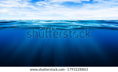 Abstract image of Tropical underwater dark blue deep ocean wide nature background with rays of sunlight and blue sky in background.