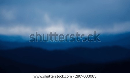 An abstract, impressionistic view of layered blue mountains under a dramatic sky filled with clouds and a bright horizon.