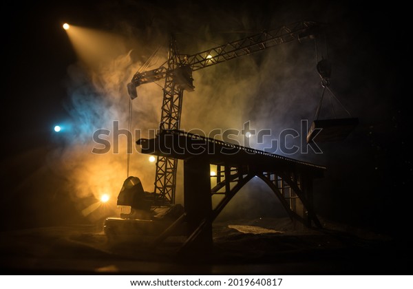 Abstract Industrial background with construction
crane silhouette over amazing night sky with fog and backlight.
Tower crane against the foggy sky at night. Industrial skyline.
Selective focus
