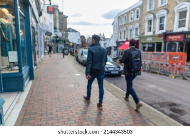 Abstract Intentionally Blurred Two Male Pedestrians On A Local High Street With A Variety Of Shops Parked Cars And Road Works With Intentional Blur