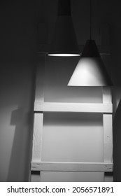 Abstract Interior Background, Hanging Spot Lights And A Wooden Ladder Are In Dark Room. Stylized Vertical Black And White Photo