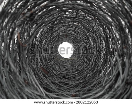 Abstract interior view looking through coiled razor wire roll with circular tunnel effect
