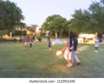 Abstract Kids Having Fun With Sparkler Fireworks And Glow At July 4th Celebration Event In Irving, Texas, USA. Diverse Group Of Local Residents Crowd Celebrate Fourth Of July At Evening