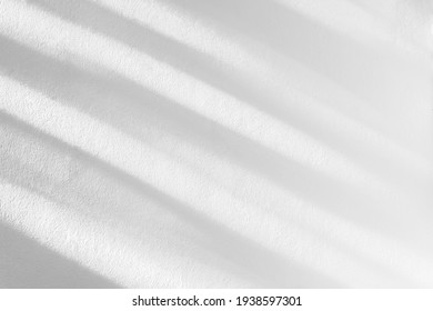 Abstract leaf and light shadow blurred background. Natural diagonal leaves tree branch shadows and sunlight dappled on white concrete wall texture for background wallpaper and design
