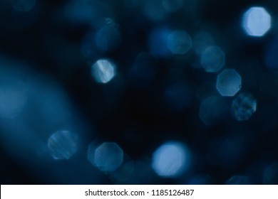 abstract lens flare on black background. blue defocused bokeh lights. glowing color burst. festive christmas backdrop. blurred flying snowflackes concept.
