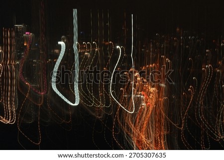 Abstract light trails in motion captured at night, featuring dynamic streaks of yellow, white, and green against a dark background. The long-exposure technique creates energetic, flowing lines 