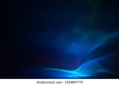 Abstract light waves with glitter effect. Shiny blurry blue lines on dark background. Defocused soft lens flare glow.