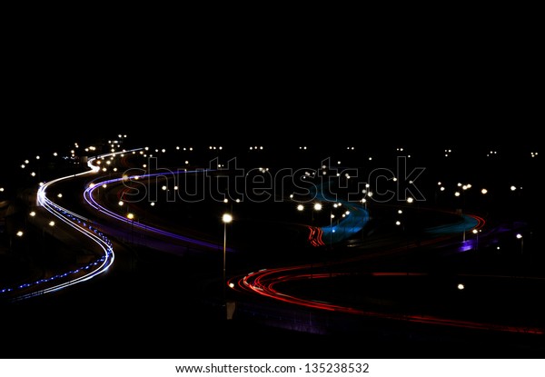 Abstract lights from an ambulance on road\
junction with bridge.
