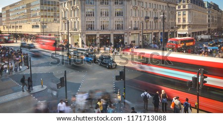 Abstract London street scene with motion blurred double decker buses and crowds of people