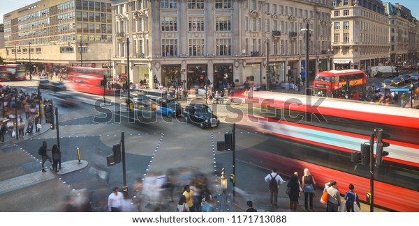 Abstract London street scene with motion\
blurred double decker buses and crowds of\
people