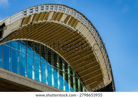 An abstract low angle view of a contemporary glass and steel building showing the underbelly of a large wave shaped roof canopy
