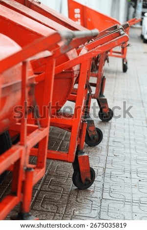 Abstract low angle view of a red industrial pushcart on a wet patterned sidewalk.