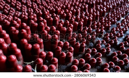 Abstract macro close-up of a red textured rubber surface featuring repeating clusters of small cylindrical nubs. This deep crimson geometric pattern background offers a heavy tactile texture with dramatic micro-shadows, ideal for industrial design, automotive backdrops, and contemporary graphic layouts.