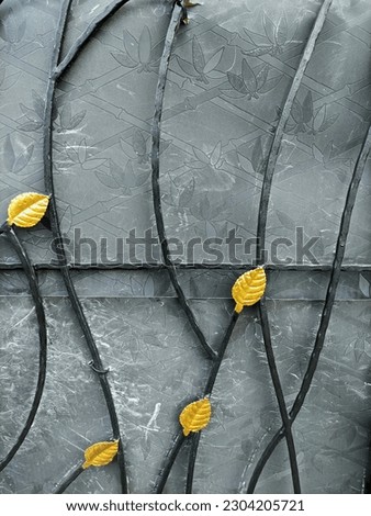 Abstract metal background with yellow leaves on a black background. Abstract background with leaves on the iron fence. Detail of a forged metal fence with yellow leaves on it. 