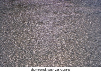 Abstract metallic color of water surface. Aerial sea surface covered with tiny choppy waves reflecting silver light. Aerial view to deep grey water in river with sunlight. Aerial view of Adriatic Sea.