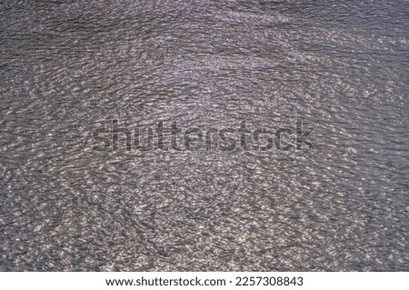 Abstract metallic color of water surface. Aerial sea surface covered with tiny choppy waves reflecting silver light. Aerial view to deep grey water in river with sunlight. Aerial view of Adriatic Sea.