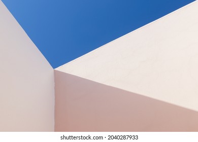 Abstract minimal architecture fragment, inner corner of pink painted walls is under blue sky