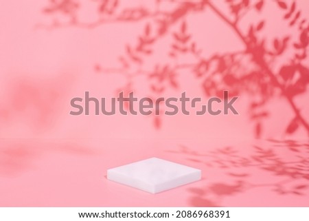 Abstract minimal nature scene - empty stage and white podium on pink background and soft shadows of rose flowers and leaves. Pedestal for cosmetic product and packaging mockups display presentation
