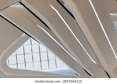 Abstract modern architecture inside Central Embassy, Bangkok, featuring sleek white escalators with LED lights, futuristic design, and glass skylight.